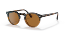 A pair of Oliver Peoples sunglasses with brown lenses and metal frame.